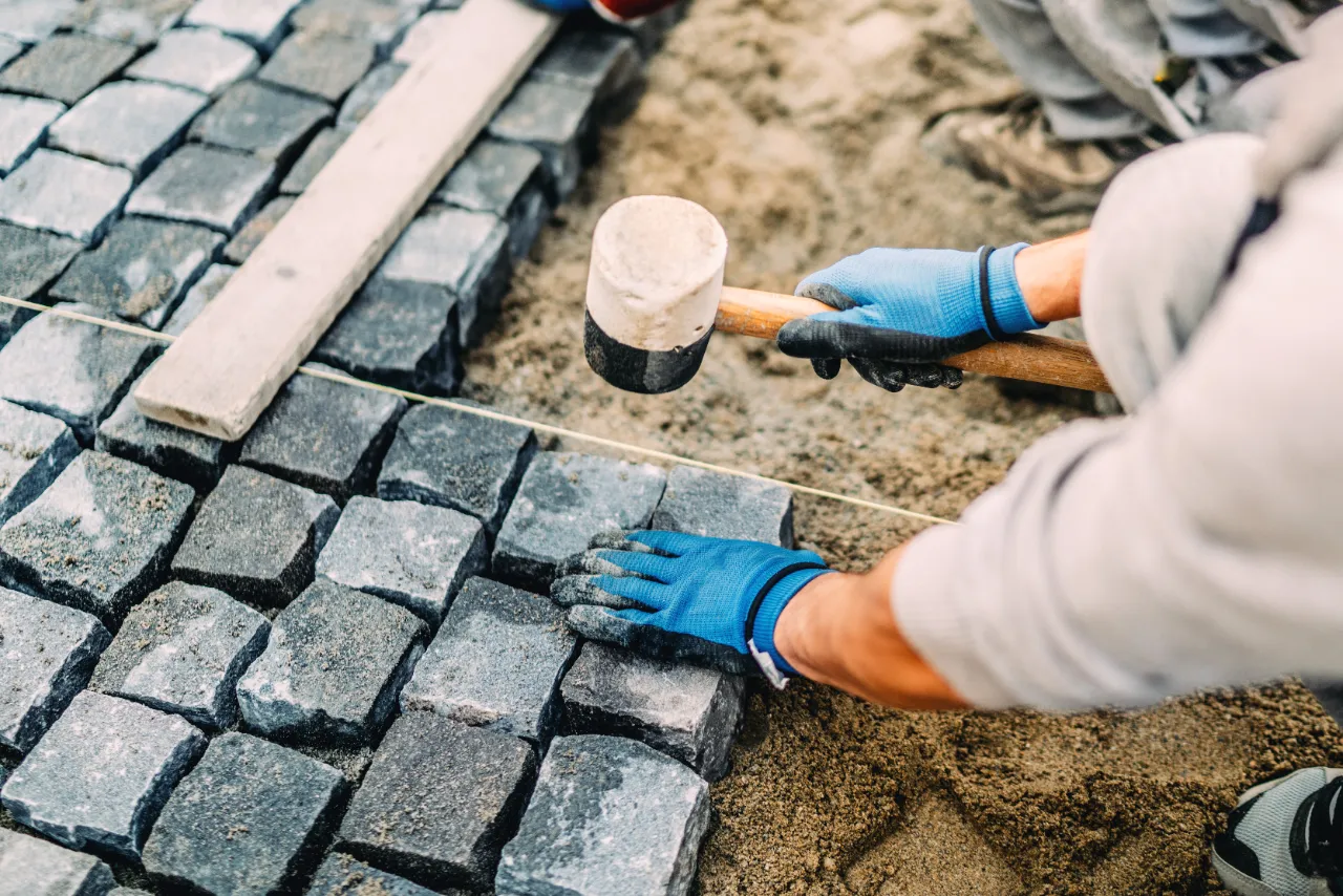 Worker laying pavers with a rubber mallet on a New Jersey project